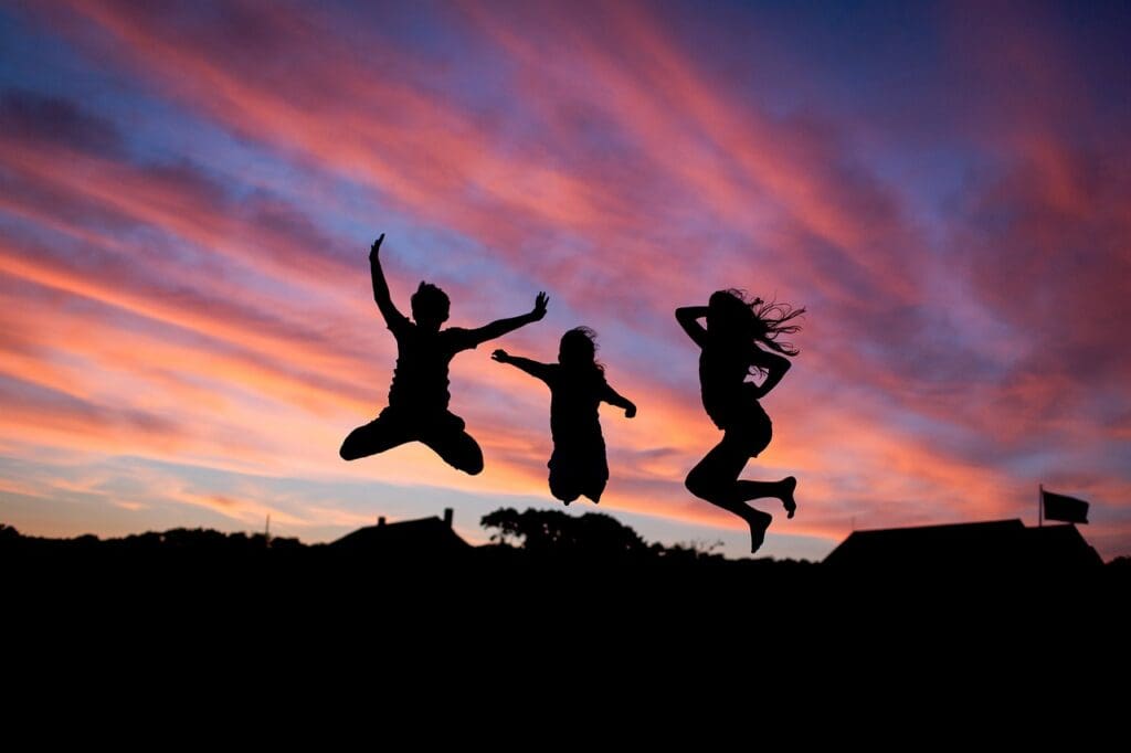 3 people jumping on a mountain with red sky