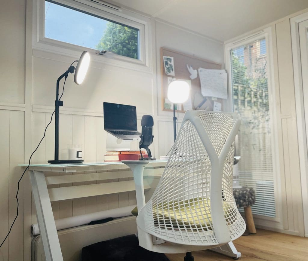 White desk and chair with laptop, microphone and backlighting
