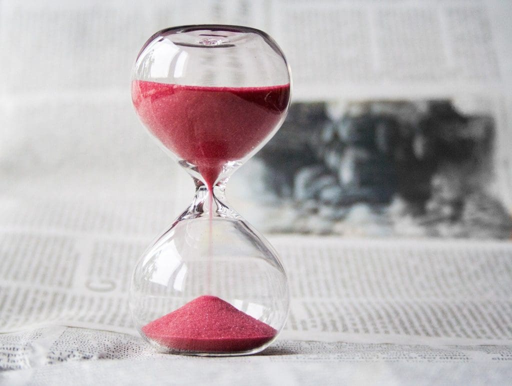 Hourglass with pink sand on a newspaper